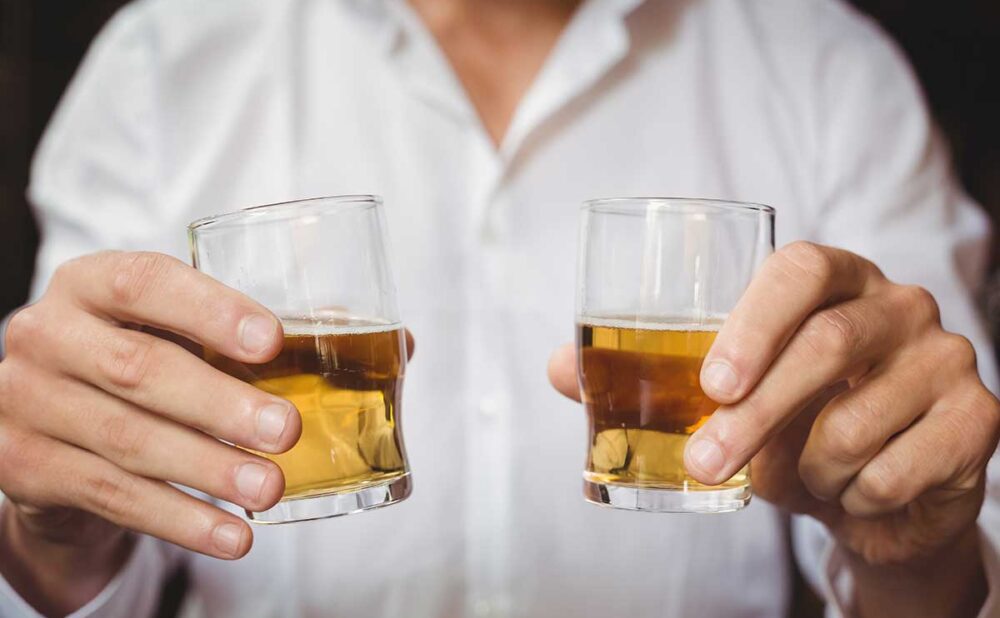 Close up of bartender holding whisky shot glasses, highlighting dram shop law in Georgia.