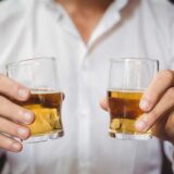 Close up of bartender holding whisky shot glasses, highlighting dram shop law in Georgia.