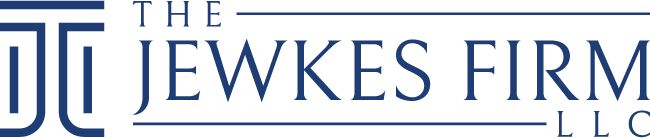 Logo for "The Jewkes Firm" with a stylized design. The graphic shows the firm name between two parallel horizontal lines, with 'The Jewkes Firm' written in bold, uppercase letters. There is also a geometric symbol resembling the letter 'J' on the left side, making it perfect for a professional header.