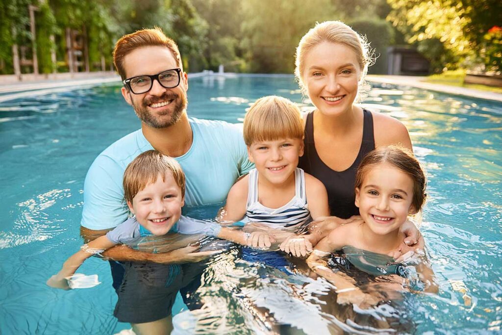 Parents Teaching Kids How To Swim In Pool