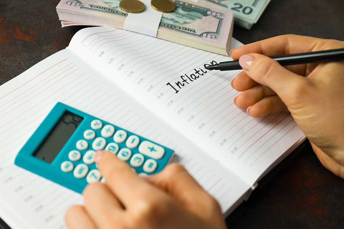 A person writing on a notebook with a calculator