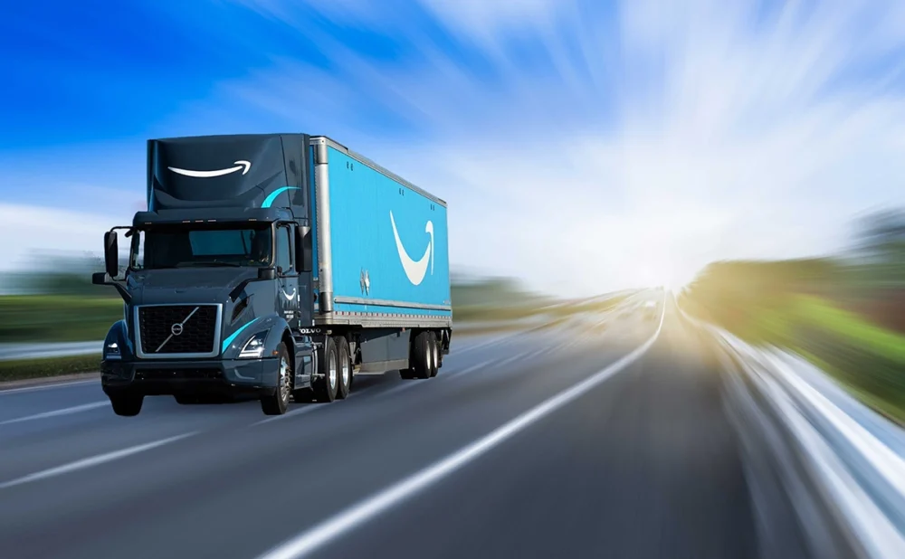 A blue Amazon delivery truck driving at high speed on a highway with a blurred background.