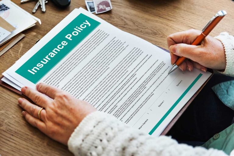 A person signing an insurance policy document at a desk, symbolizing the top 10 worst insurance companies.