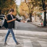 A woman uses her phone while crossing the street, highlighting pedestrian safety concerns in Georgia.