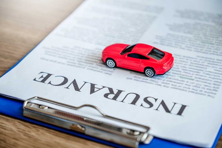 Red toy car on top of an insurance document on a clipboard, symbolizing the worst insurance companies.