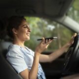 A woman driving while illegally holding a cell phone, highlighting some of the unique driving laws in Georgia.