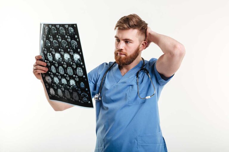 A doctor in a blue scrubs holds a CT scan, focusing on traumatic brain injuries for medical analysis.