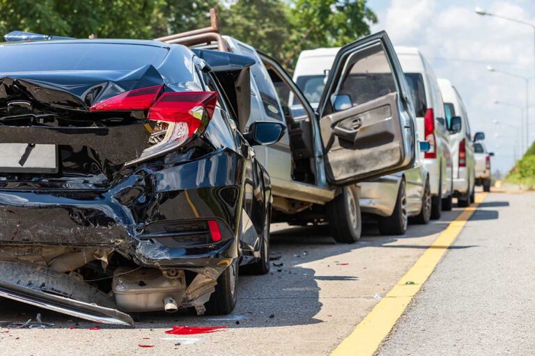 A line of damaged cars sits in the middle of the road, highlighting the complexities of proving fault in multi-vehicle accidents.