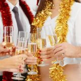 A group of people joyfully toasting champagne glasses at a festive Christmas party, embracing the spirit of safe holiday driving.