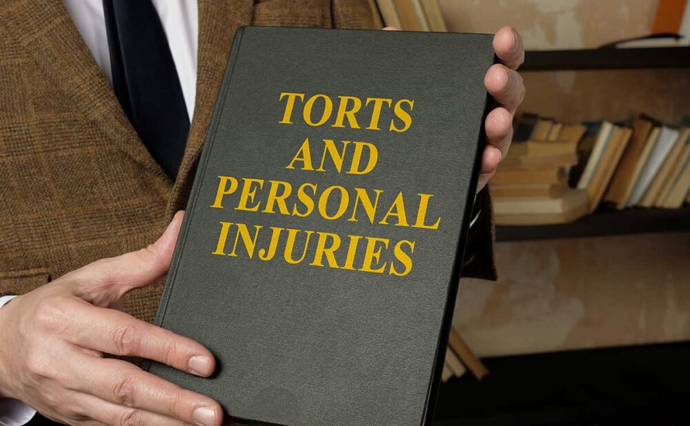 Man holding a book titled "Torts and Personal Injuries," depicting the impact of tort reform on personal injury rights in Georgia.