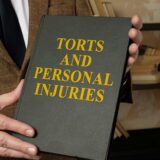 Man holding a book titled "Torts and Personal Injuries," depicting the impact of tort reform on personal injury rights in Georgia.