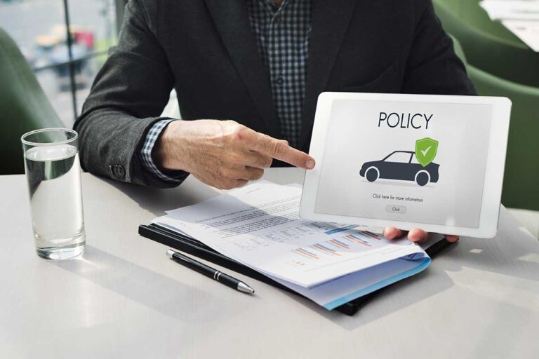 A man in a suit holds a tablet displaying the word "policy," symbolizing the need to understand your car insurance policy.