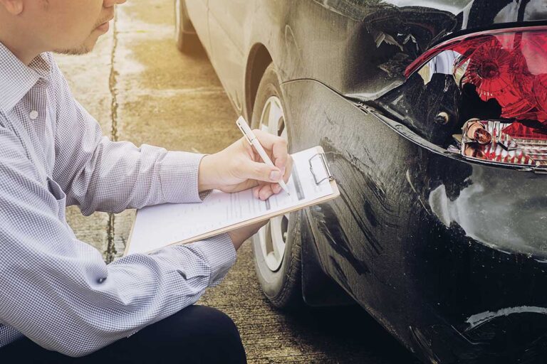 An insurance agent surveys damage after a car accident, underscoring the importance of decoding fault and no-fault insurance in Georgia.