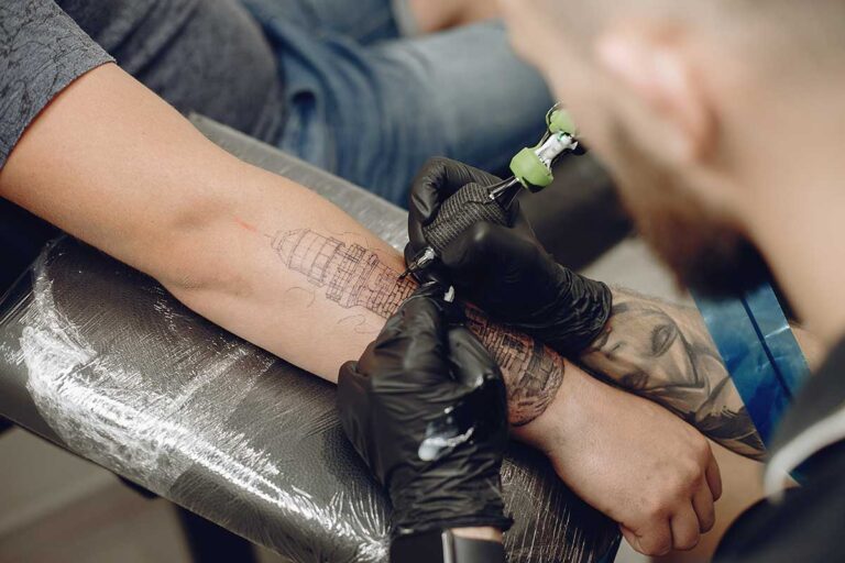 A man in the process of getting a tattoo on his arm, emphasizing the need for awareness about tattoo infections.