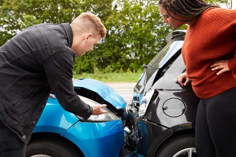 A man and woman assess damages after a car collision, underscoring the importance of understanding uninsured and underinsured motorist laws in Georgia.