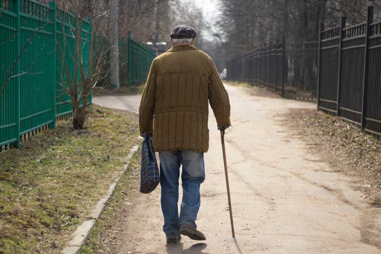 An old man navigates a path with a cane, emphasizing the need for awareness regarding wandering and elopement risks.