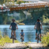 Three children biking on a path next to Lake Peachtree, emphasizing the enjoyment and hazards for cyclists in Peachtree City.