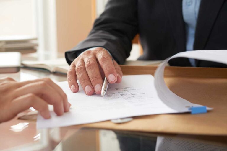 Two individuals are engaged in signing documents, focusing on a settlement demand letter for a personal injury case.