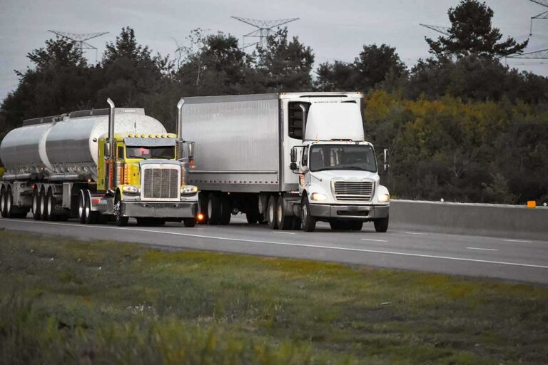 Two semi trucks driving side by side on a highway.