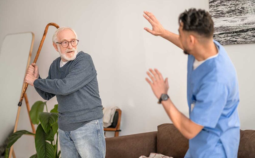 An elderly man holding a cane threatens a care giver, highlighting nursing home abuse in Georgia.