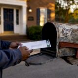 Hands placing certified mail in mailbox